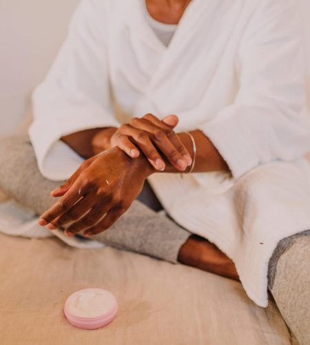 Woman applying lotion in a cozy setting, embracing self-care and relaxation.